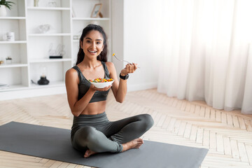 Young indian woman eating healthy salad after workout