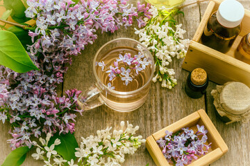 Essential oil and a cup of tea made from lilac flowers - 656666940
