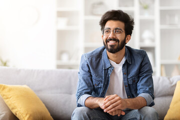 Smiling Young Eastern Guy Relaxing On Couch In Living Room At Home