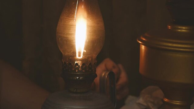 a boy lights an old kerosene lamp