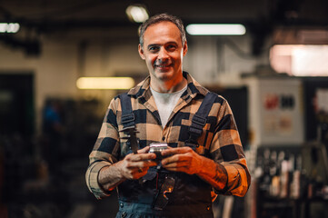 A portrait of a metallurgist holding a metal part and a measuring tool.