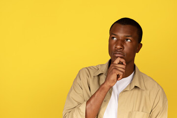 Pensive serious millennial african american guy in casual thinking, looking at free space