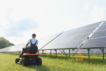 A man mows the grass near the solar panels. Green energy