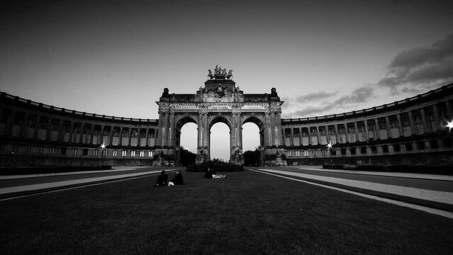 Brussels, Belgium 08 04 2023: Romantic black and white sunset time lapse of the Cinquantenaire Park the lights turning on as the sun goes down. Colours of sunset and night arch of peace