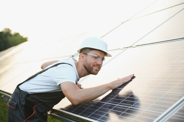 Man engineer in uniform working on solar panels power farm. Solar panel field. Clean energy production. Green energy.