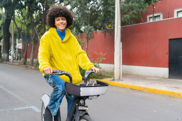 man afro mexican smiling to the camera riding on a rented bicycle on the street at mexico city