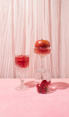 Still life arrangement of cristal glasses filled with red apples and celosia flower. Creative copy space