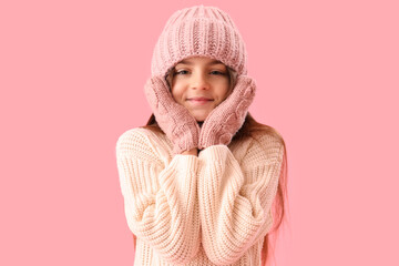 Cute little girl in winter clothes on pink background