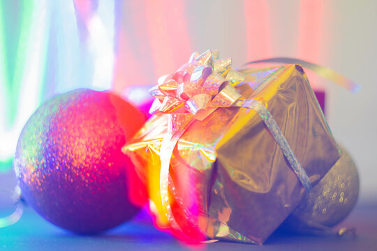 New Year's gift in a bright package against the background of Christmas decorations and bright lights of the garland.