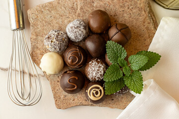 Homemade chocolate truffles on a stone with mint leaves