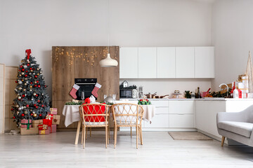 Interior of modern kitchen with Christmas tree, gifts and served table