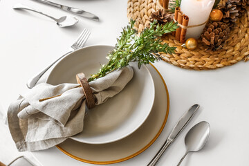 Christmas table setting with folded napkin, clean plates and cutlery, closeup