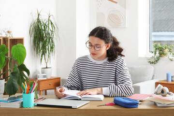 Female student reading schoolbook at home