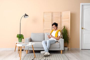 Young Asian man using mobile phone on his day off at home - Powered by Adobe