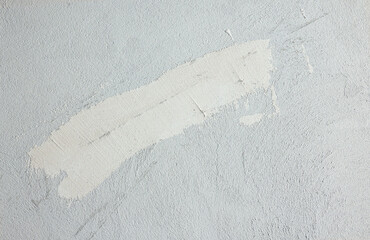 Fragment of a gray plastered wall indoors. The crack on the wall is covered with white putty...