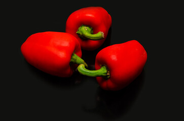 Red pepper. Several ripe red bell peppers on a black background, vegetables, sweet pepper
