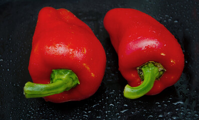 Red pepper. Several ripe red bell peppers with dew drops on a dark background, vegetables, sweet pepper