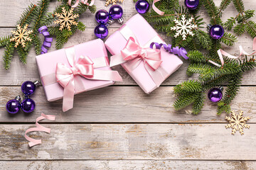 Christmas tree branches with balls, snowflakes and gift boxes on grey wooden background