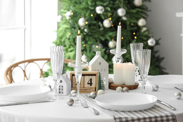 Festive table setting with burning candles and Christmas decor