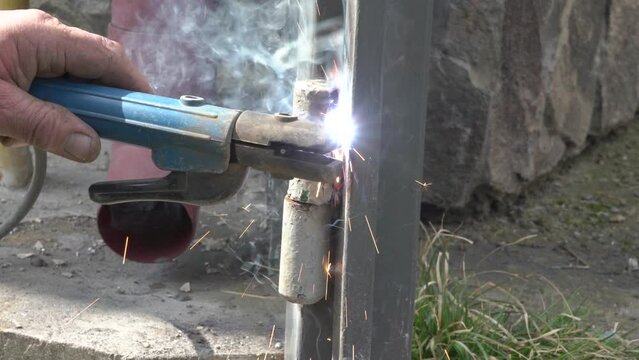Welding A Gate Hinge,sparks from welding a gate, a welder works in the yard