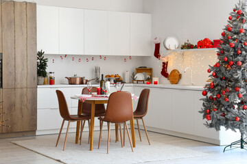 Interior of modern kitchen with festive table setting, Christmas tree and decor