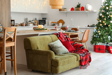 Interior of modern kitchen with Christmas decorations and green sofa