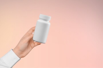 Human hand holding white blank bottle. Packaging for supplements.