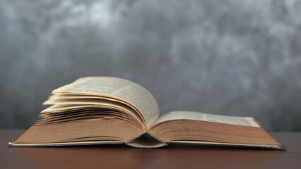 Open book side view mockup. Realistic flipping pages. An ancient book opened on a wooden table that was opened by the passing wind.