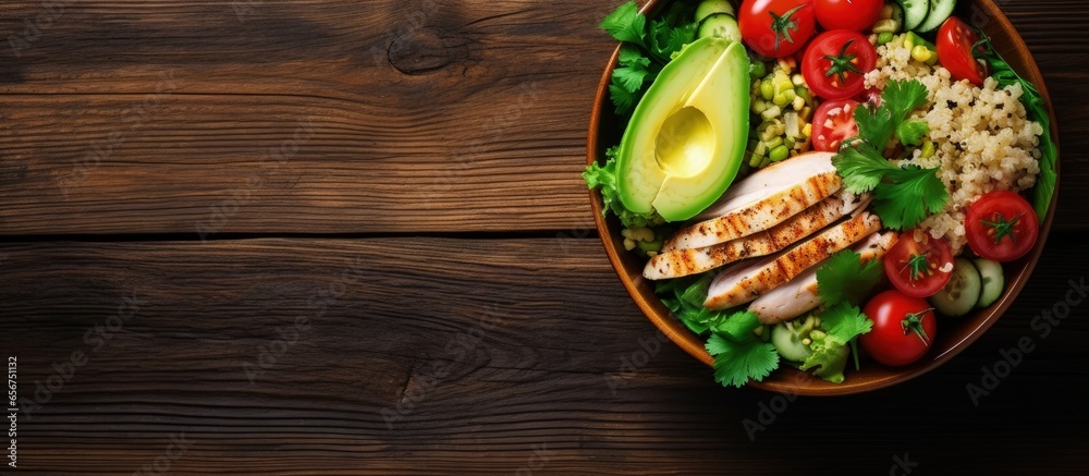 Sticker nourishing bowl of salad with quinoa chicken avocado and mixed greens on wooden background with copy