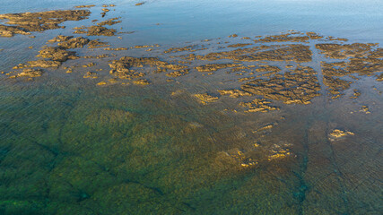 Aerial photo of the island of Isola Piana near Stintino and the beach of Spiaggia La Pelosa. Mountainous island, blue water and clear sky.