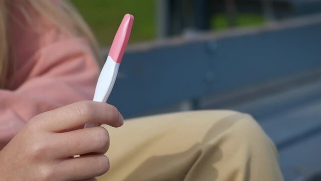 Girl with abortion pills. A view of depressed teen sitting with pregnancy test and abortion pills in her hands.