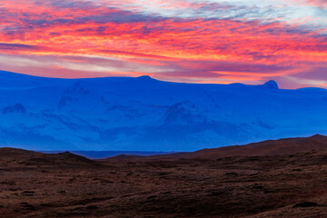 Icelandic chilly highlands with stunning sunset, concept for night photography. Breathtaking view of rosy cotton candy like sky due to sun setting above grand nordic mountain ranges.