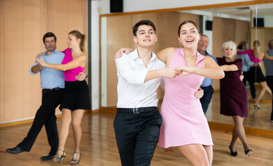 Dynamic young pair engaging in Latino dance in dance studio. Pairs training ballroom dance in hall