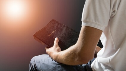 Young man holding bible book on sun light.