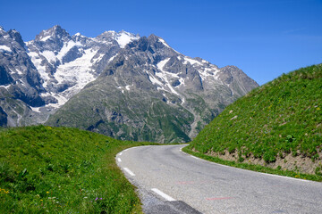 Narrow mountains road from Col de Lautaret to Col du Calibier, Mountains and alpine meadows views of Massif des Ecrins, Hautes Alpes, France in summer