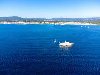 Aerial view on blue water of Gulf of Saint-Tropez, sail boats, houses of Port Grimaud, Port Cogolin, summer vacation in Provence, France