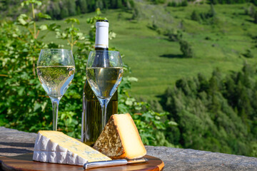 Cheese and wine, glasses of dry white Roussette de Savoie and Vin de Savoie wine from Savoy region,...