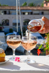 Wine and cake of French Riviera, glasses of cold rose Cote de Provence wine and Tarte Tropezienne cake in yacht harbour of Port Grimaud, summer vacation  in Provence, France.