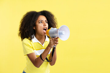 Young angry African American woman holding megaphone screaming laud about sale isolated on yellow...