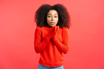 Portrait of serious African American woman wearing winter gloves feeling cold isolated on red background