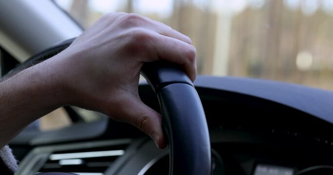 Man's hand lies on the steering wheel of a car in motion. Concept of training in a driving school, traveling by car.
