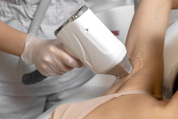 Cosmetologist make laser hair removal on woman's underarm