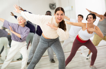 Smiling attractive young girl visiting group choreography class, learning modern dynamic dances....