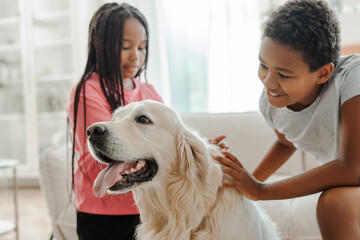 Happy kids sitting in the living room with pet. Animal care, childhood concept