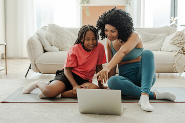 Happy mother and her little daughter training online while using laptop. Healthy lifestyle, vitality, family concept