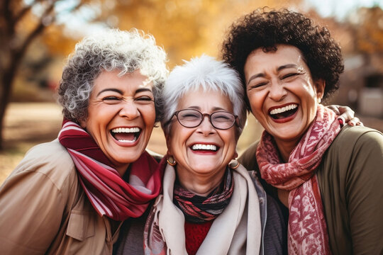 Portrait and close up of three old mature women having fun laughing and having a good time together outdoor. Senior friendship concept lifestyle. African and caucasian

