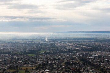 Suburban Houses in Morning Mist with a Distant Smoke Plume