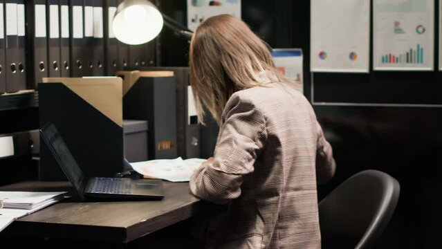 Caucasian policewoman inspecting evidence, reviewing records, and utilizing technology in a well-organized office space. Dedicated investigator analyzes witness statements and records to solve crime.