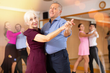 Spirited old pair training waltz dance during workout session. Pairs training ballroom dance in hall