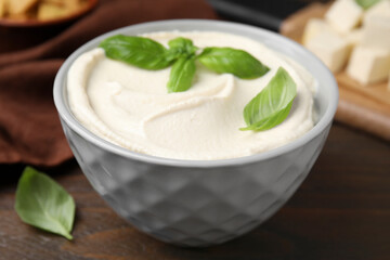 Delicious tofu sauce and basil leaves in bowl on wooden table, closeup